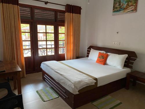 a bedroom with a bed with an orange pillow on it at Why Not Palace in Anuradhapura
