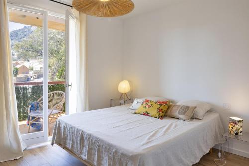 ein weißes Bett in einem Zimmer mit einem großen Fenster in der Unterkunft Casa Rose in Biguglia