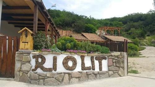 uma parede de pedra com um sinal em frente a uma casa em Riolit Barlangszállás Szomolya em Szomolya