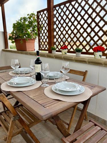a wooden table with plates and wine glasses on it at La Casetta tra Alghero e Stintino in Palmadula