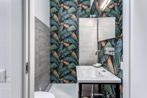 a bathroom with a sink and a leafy wallpaper at AltaDomus Roma in Rome