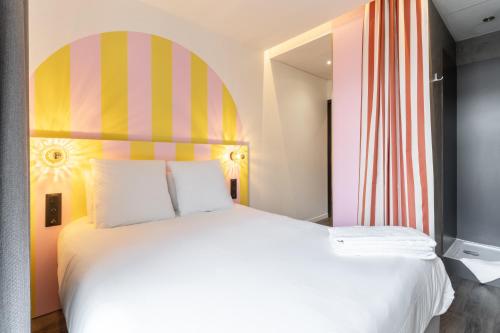 a bedroom with a large white bed with a colorful headboard at DEMAIN Hôtel & Conciergerie in Nantes