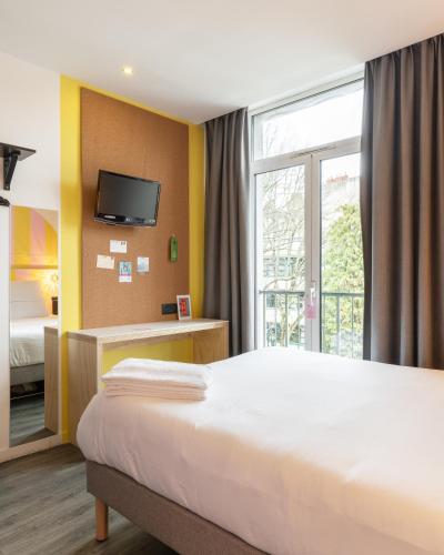 a hotel room with a bed and a window at DEMAIN Hôtel in Nantes