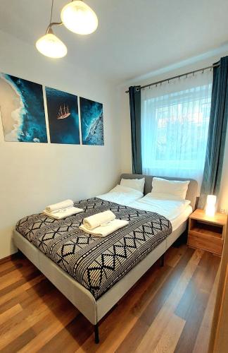 a bedroom with a bed with two towels on it at Apartament PrzyLesie Jantar by TriApart in Jantar