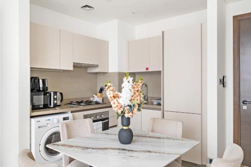 a white kitchen with a table with a vase of flowers at Beautiful 2 bedroom next to Business Bay - Sobha Creek Vista in Dubai