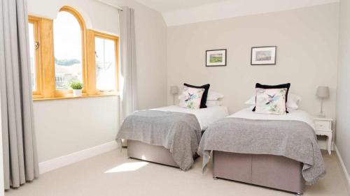 een witte kamer met 2 bedden en een raam bij Roslyn in Bakewell