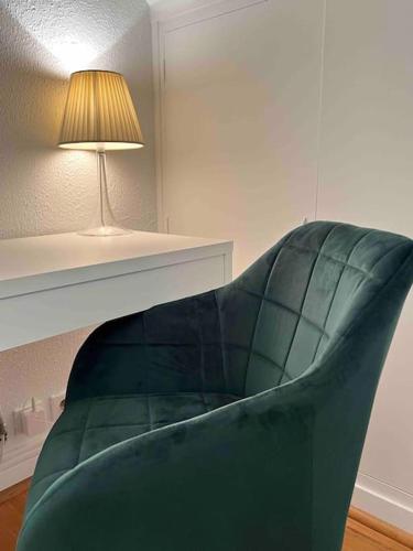 a green couch in a living room with a lamp at Grand appartement en centre ville in Gouvieux