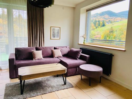 un sofá púrpura en una sala de estar con ventana en Villa Makuchówka, en Korbielów