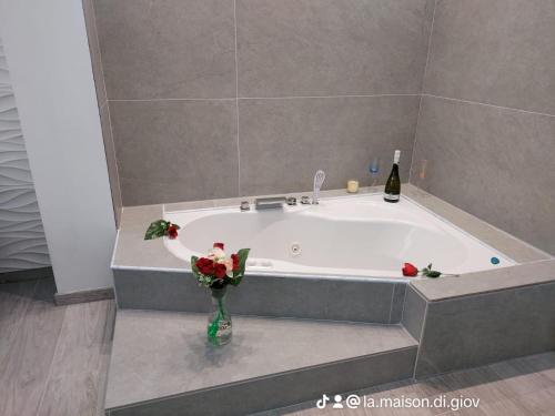 une baignoire avec un vase de fleurs et une bouteille de vin dans l'établissement La Maison di Giovanni, à Comiso