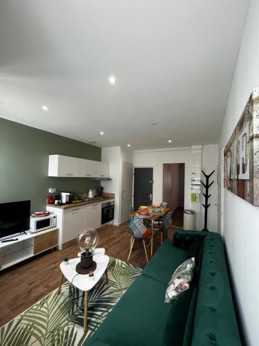 un salon avec un canapé vert et une cuisine dans l'établissement La maison castelpontine T3, à Pont-du-Château