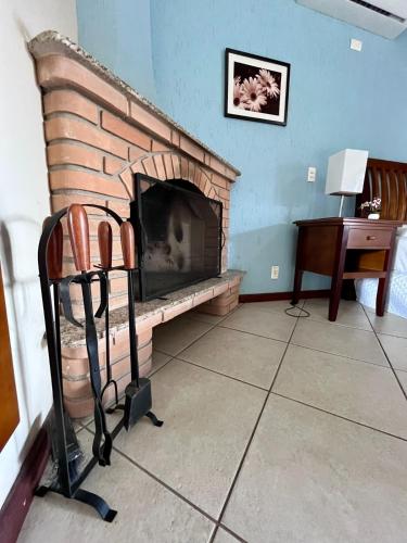 a living room with a brick fireplace and a desk at Pousada Finlândia in Penedo