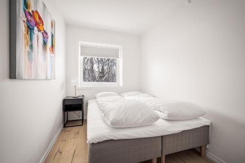 a bedroom with a bed with white sheets and a window at Gullstein in Geilo