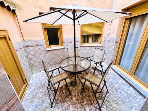 a table and chairs with an umbrella on a patio at APARTAMENTOS TURISTICOS MONTASOL in Montánchez