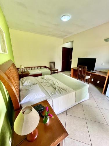 a bedroom with a bed and a table with a lamp at Pousada Finlândia in Penedo