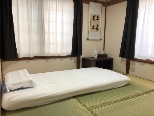 a large bed in a room with two windows at 東京昭島迎賓館 in Akishima