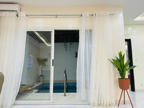 a sliding glass door with white curtains in a room at Sall Residence Mbour Saly in Mbour