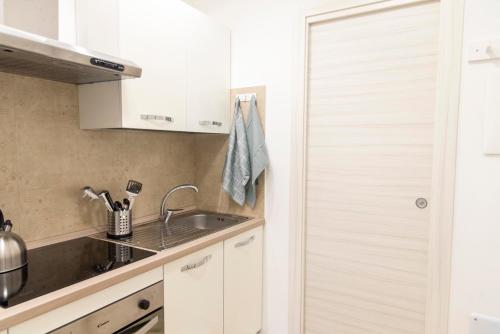 - une cuisine avec des placards blancs et un évier dans l'établissement KAMCHŪ RESIDENCE: VIA DEI LAGHI - APT #R5, à Ciampino