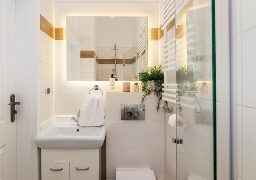 a white bathroom with a sink and a mirror at Malila Premium Apartments City Center Kazimierz Starowiślna 41 in Krakow