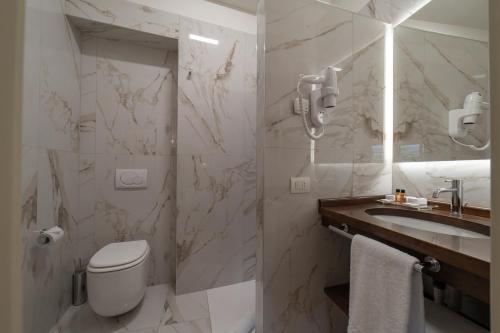 a white bathroom with a toilet and a sink at Hotel Palazzo San Niccolò & Spa in Radda in Chianti