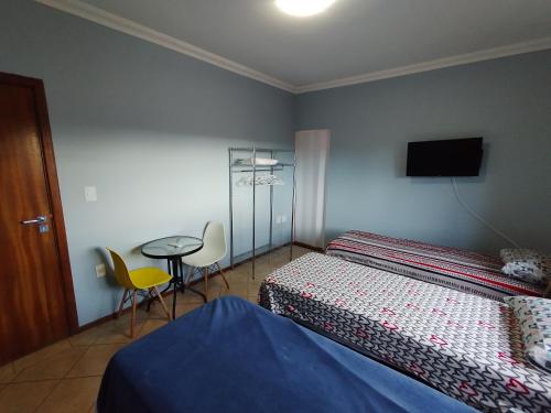 Schlafzimmer mit einem Bett, einem Tisch und einem TV in der Unterkunft Pousada Indi in Ribeirão Preto