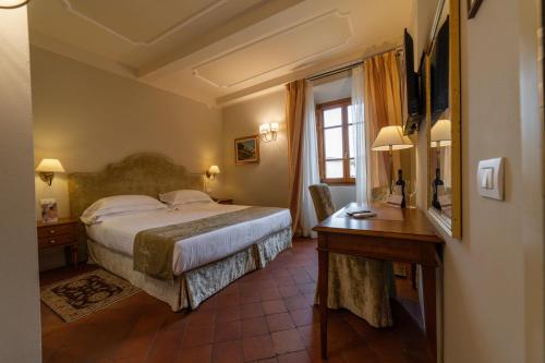 a hotel room with a bed and a desk at Hotel Palazzo San Niccolò & Spa in Radda in Chianti