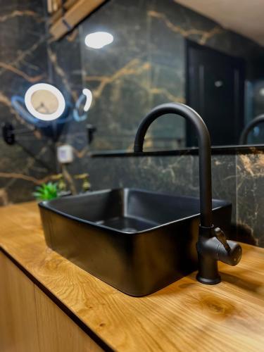 um lavatório preto num balcão de madeira numa cozinha em סוויטת Gadish em Bete-Seã