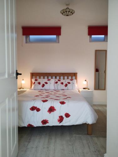 Un dormitorio con una cama con flores rojas. en The Milk Barn, en Ashbourne