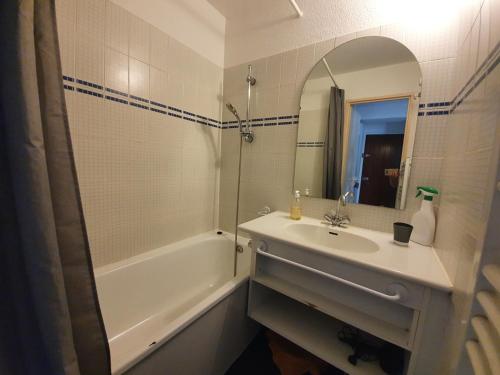 une salle de bain avec un lavabo, une baignoire et un miroir dans l'établissement Duplex plein sud pieds des pistes, à Tignes