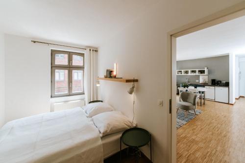 ein weißes Schlafzimmer mit einem Bett und einem Esszimmer in der Unterkunft Josty Brauerei Appartements in Berlin