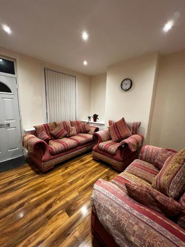 a living room with couches and a clock on the wall at Nice house near cricket ground in Nottingham