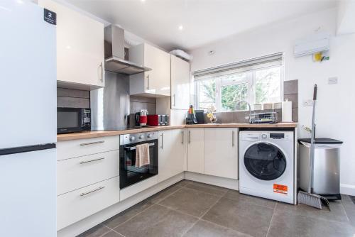 a kitchen with white cabinets and a washer and dryer at 3 Bedroom Terraced House in Beeston Ideal for Corporate Stays in Beeston