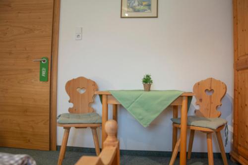 una mesa y dos sillas con un mantel verde. en Gästehaus Familie Gebhard Schädle en Grän