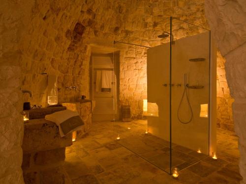 uma casa de banho com um chuveiro num edifício de pedra em Nina Trulli Resort em Selva di Fasano