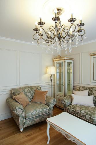 a living room with two couches and a chandelier at Boutique Apartments Siguldas in Liepāja