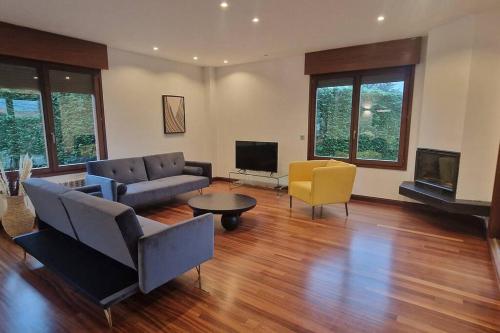 a living room with a couch and chairs and a tv at 1A119 El Sangar Somio in Gijón