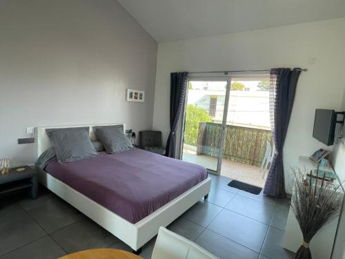 een slaapkamer met een bed en een deur naar een balkon bij Plage à 400 m Studio tout confort Terrasse Clim Parking in Hyères