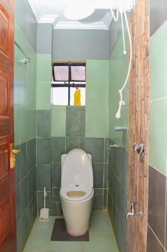a bathroom with a toilet in a green tiled room at Tamwe ltd agency in Meru