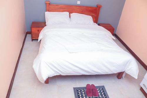 ein Schlafzimmer mit einem Bett mit zwei roten Schuhen auf dem Boden in der Unterkunft Tamwe ltd agency in Meru