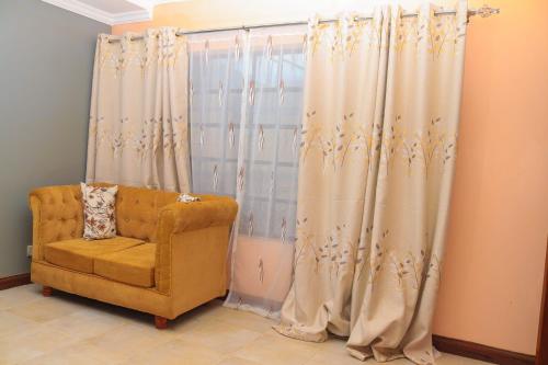 Zimmer mit einem Stuhl und einem Fenster mit Vorhängen in der Unterkunft Tamwe ltd agency in Meru