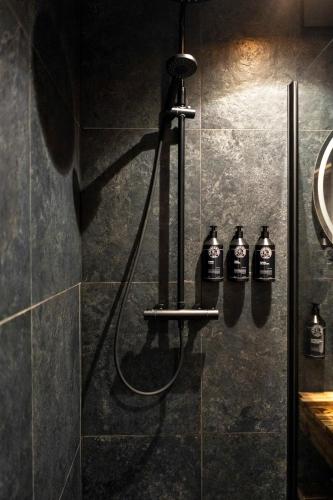 a bathroom with a shower with three bottles of alcohol at ZEBRUS RESORT in Zebras Muiža
