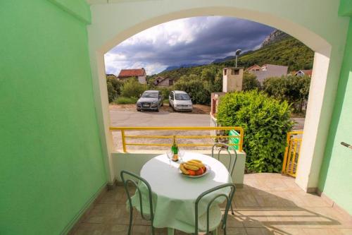a table with a bowl of fruit on a balcony at Apartments Natalika in Podaca