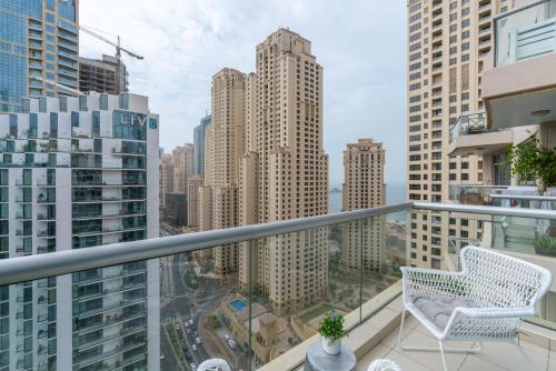 - un balcon avec une chaise blanche et certains bâtiments dans l'établissement Ultimate Stay / Full Marina Views / High Floor / Perfect Vacation / Infinity Pool / 6 People, à Dubaï