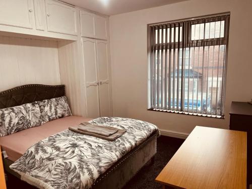 a bedroom with a bed and a table and a window at Holiday House Near Football Ground in Nottingham