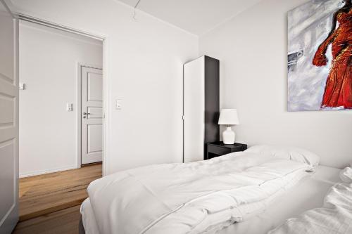 a white bedroom with a white bed and a painting at Gullstein in Geilo