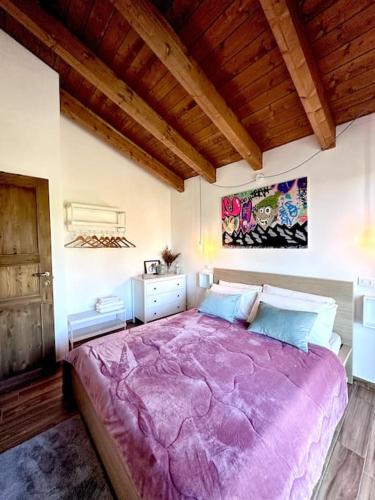 uma grande cama roxa num quarto com tecto em madeira em Vista suggestiva sulle montagne! em Ovindoli