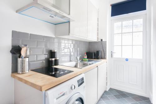 eine Küche mit einer Spüle und einer Waschmaschine in der Unterkunft Budget City Center Apartment Aldgate - Tower Bridge in London