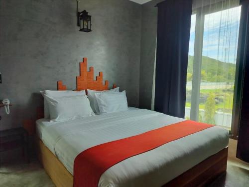 a bedroom with a large bed with a large window at Cicada Hotel Kanchanaburi in Kanchanaburi