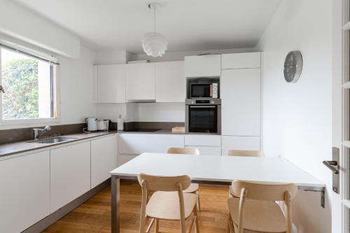 ドーヴィルにあるMagnificent 8P2BR apartment with indoor pool and garden - Deauvilleの白いキャビネット、テーブルと椅子付きのキッチンが備わります。