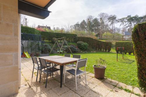 - une table et des chaises sur une terrasse avec une cour dans l'établissement 3 bedroom apartment with garden and swimming pool, à Deauville