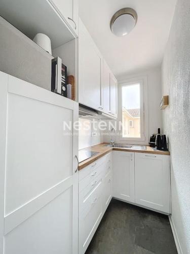 une cuisine blanche avec des armoires blanches et une fenêtre dans l'établissement 3278-T2 à 50m de la plage, à Argelès-sur-Mer